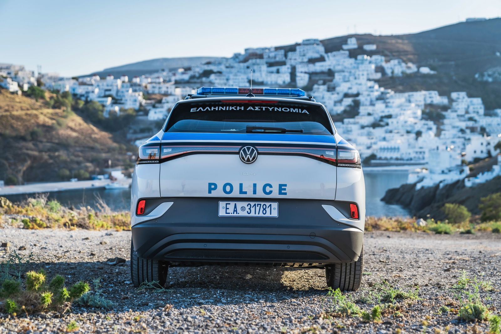 Ein Volkswagen-Polizeifahrzeug der griechischen Polizei, mit Blick auf eine Küstenstadt mit weißen Gebäuden.