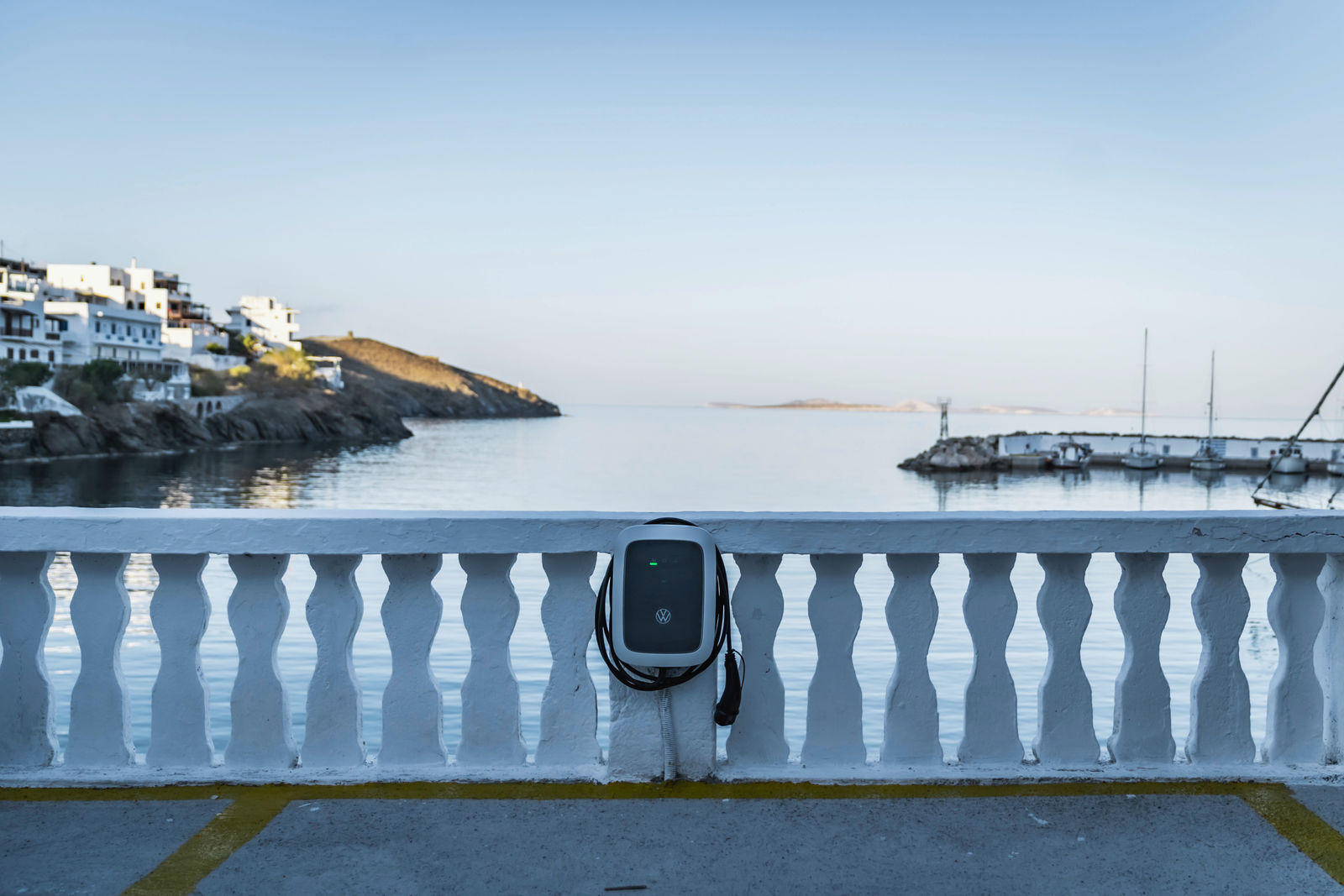 Volkswagen-Ladestation an einer weißen Balustrade mit Blick auf das Meer.