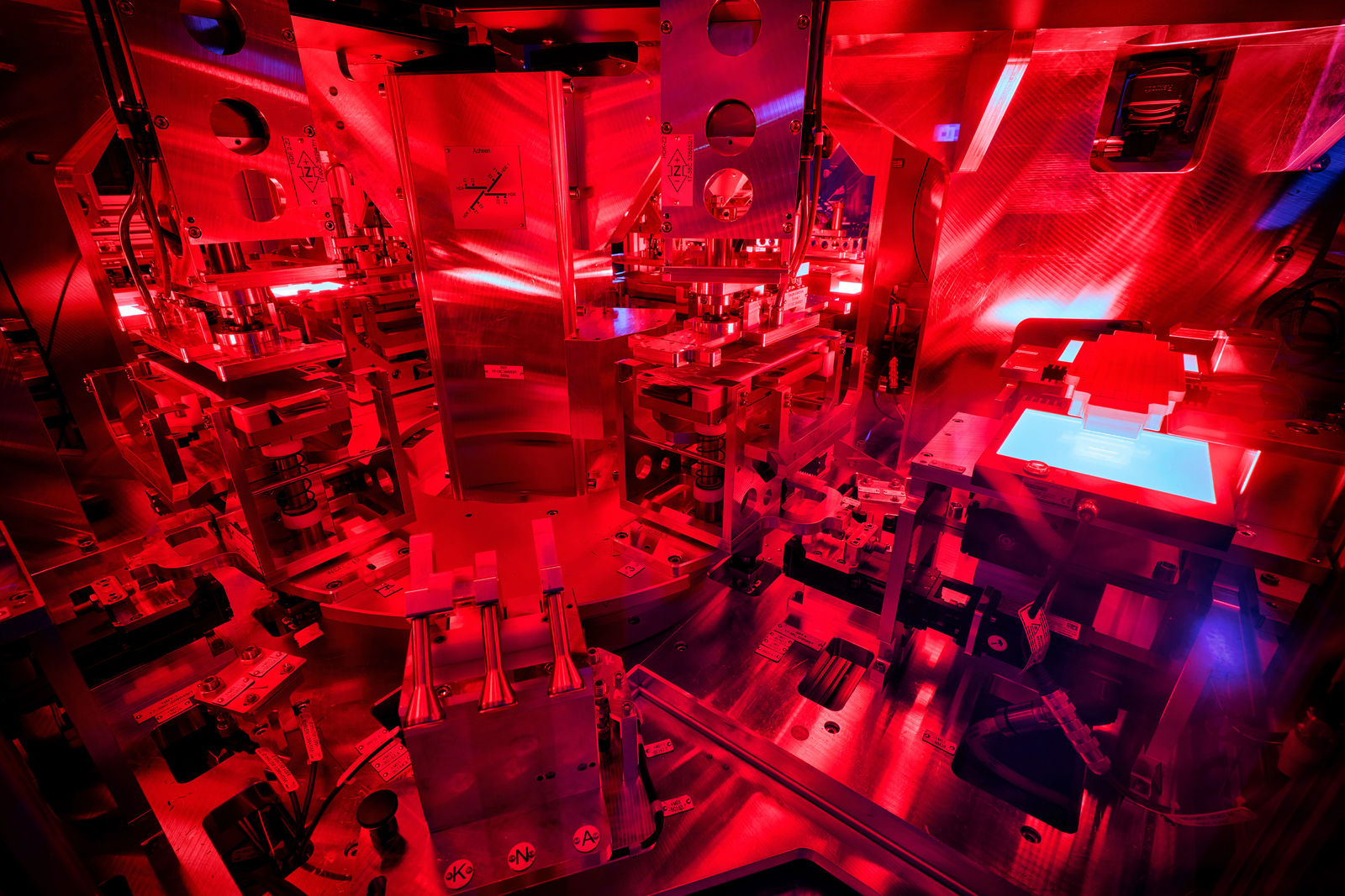 Close-up of a high-tech manufacturing machine with intense red lighting in an advanced production environment.