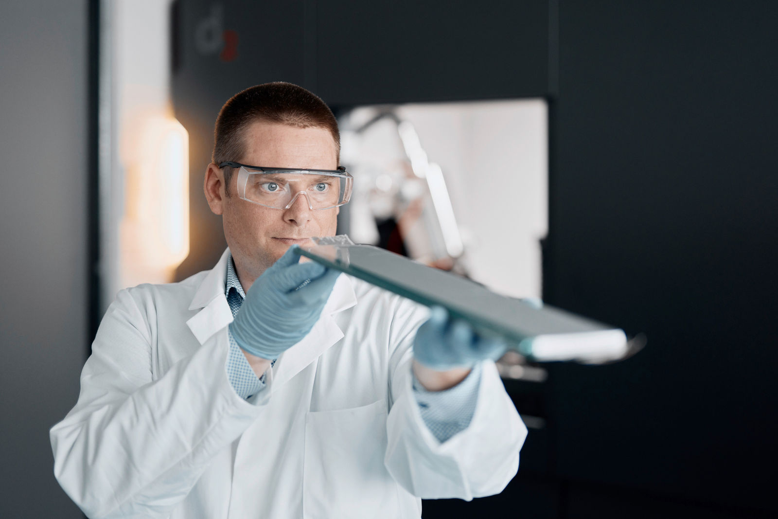 Ein Wissenschaftler in Schutzkleidung inspiziert eine Batteriezelle in einem Hightech-Labor.