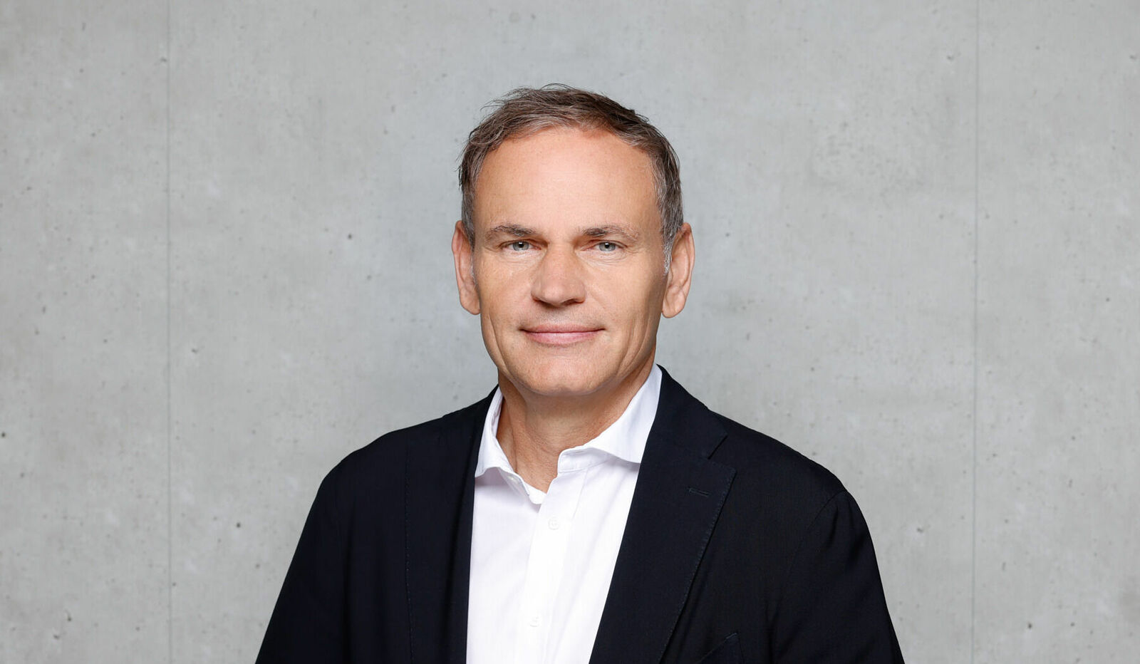 Portrait von Oliver Blume, CEO Volkswagen Group vor grauem Hintergrund