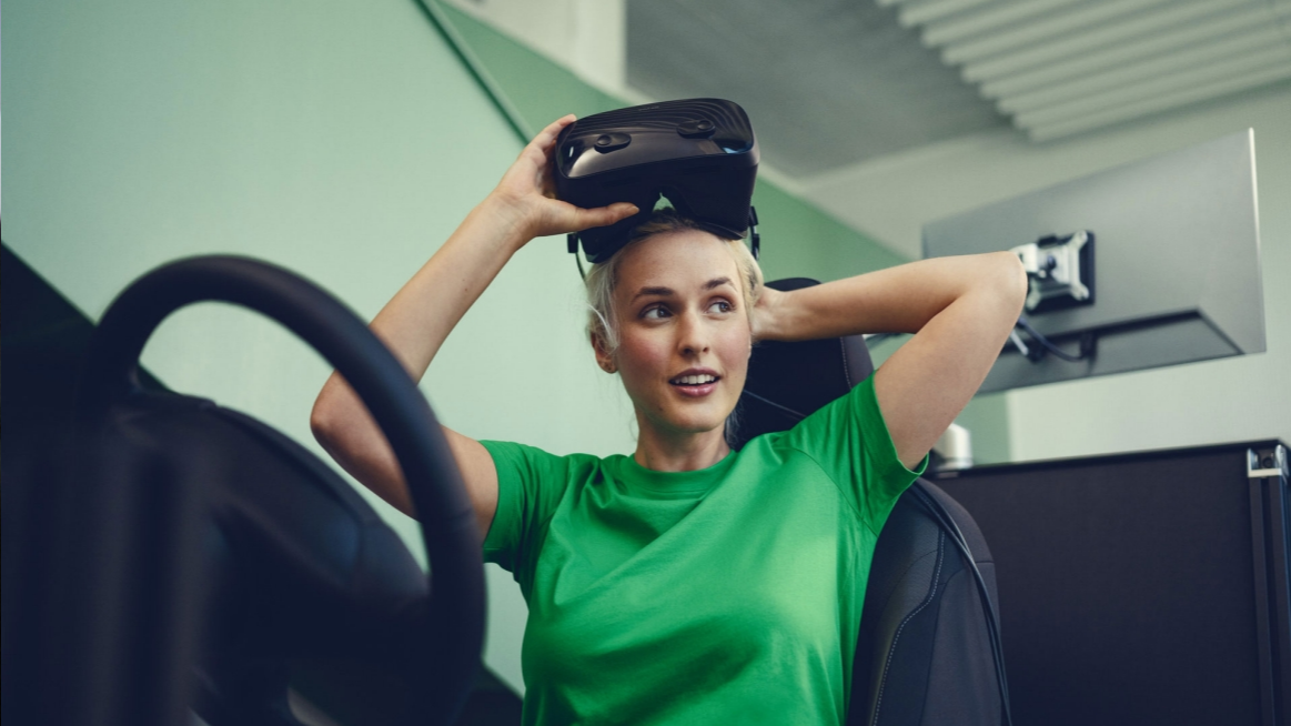 Frau sitzt in einem Auto und zieht eine VR-Brille an.