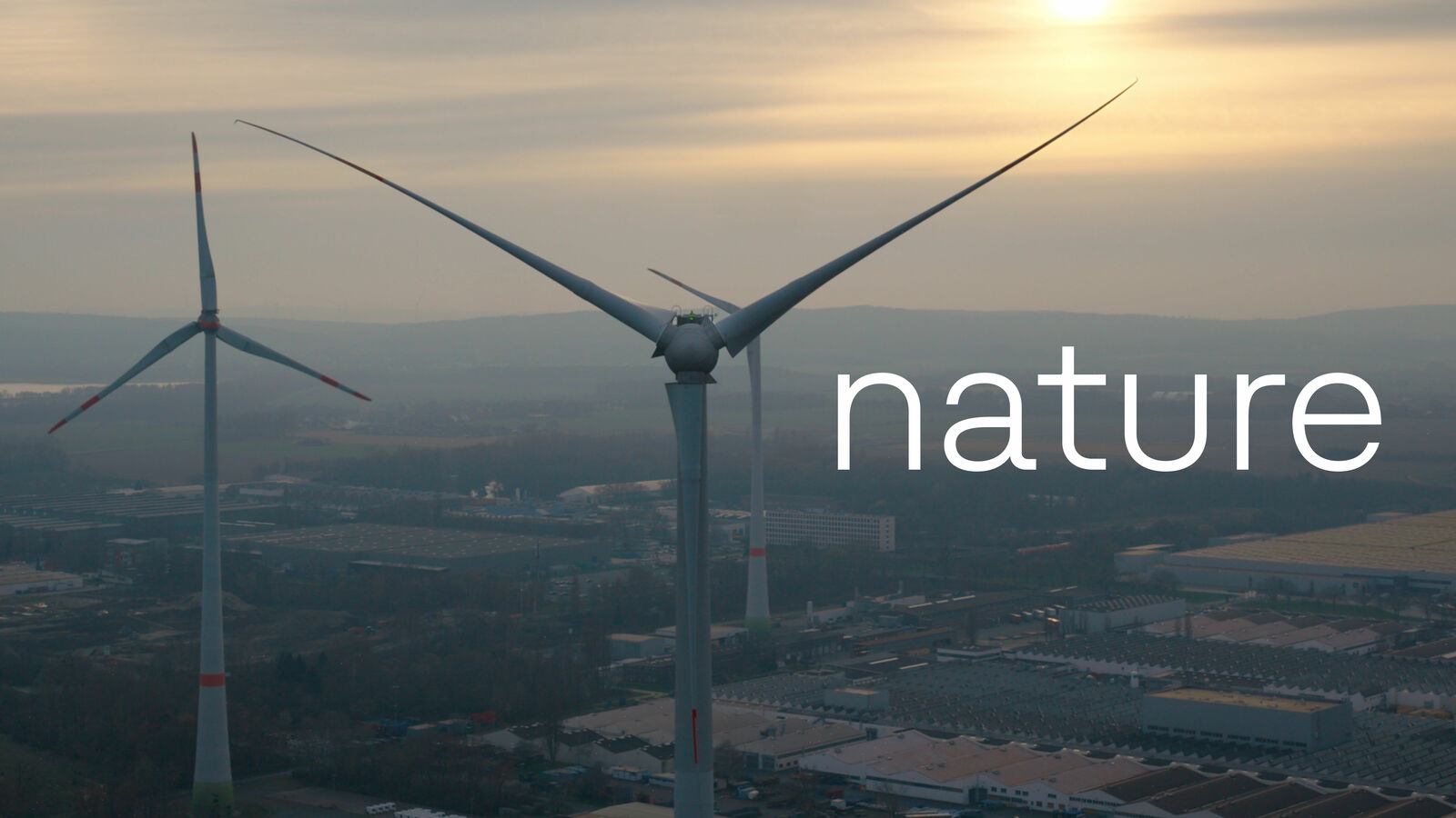 Wind turbines at sunset with the word "nature" overlaying the image.