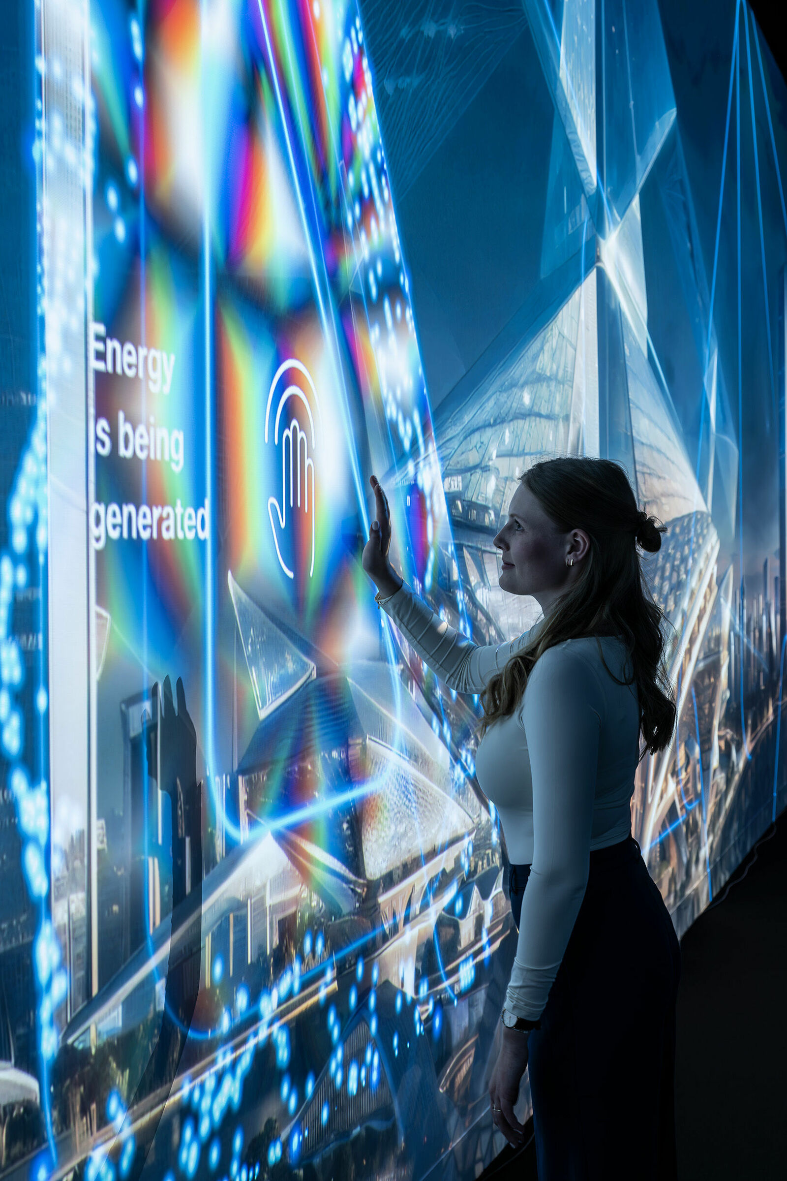 Junge Frau berührt interaktive, leuchtende Displays mit futuristischen Grafiken zur Energieerzeugung