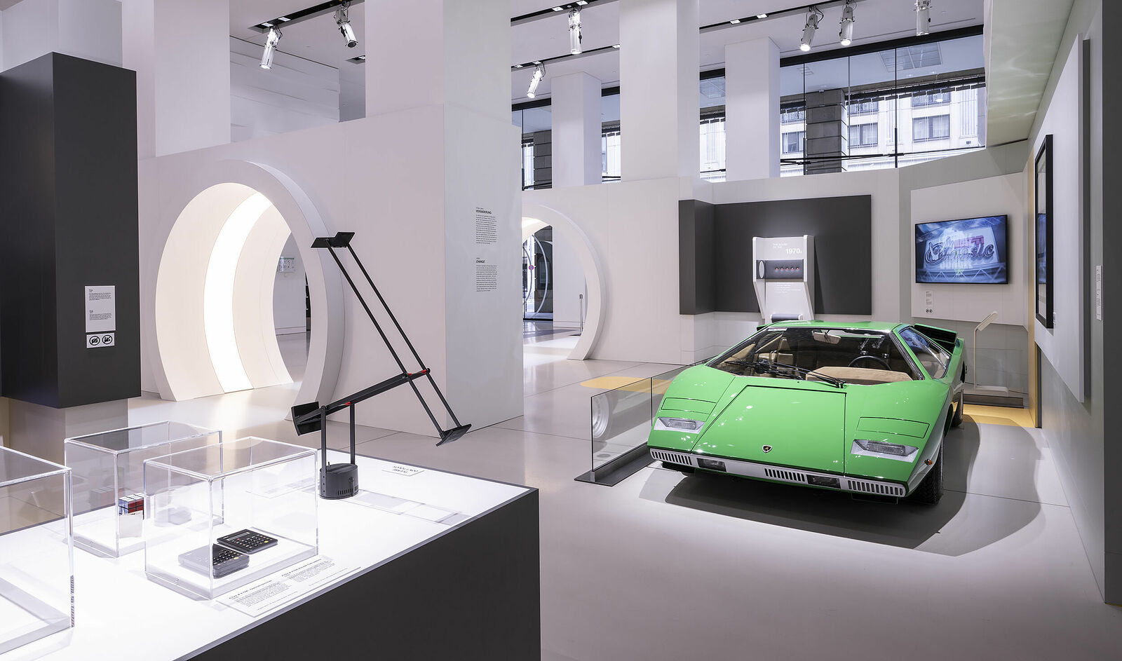 Interior view of a car museum featuring a lime green Lamborghini, surrounded by informational displays.