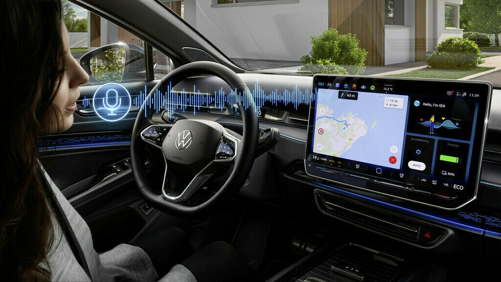 Woman sitting in the driver's seat of a Volkswagen vehicle, looking at a futuristic dashboard displaying interactive voice recognition and a navigation map.