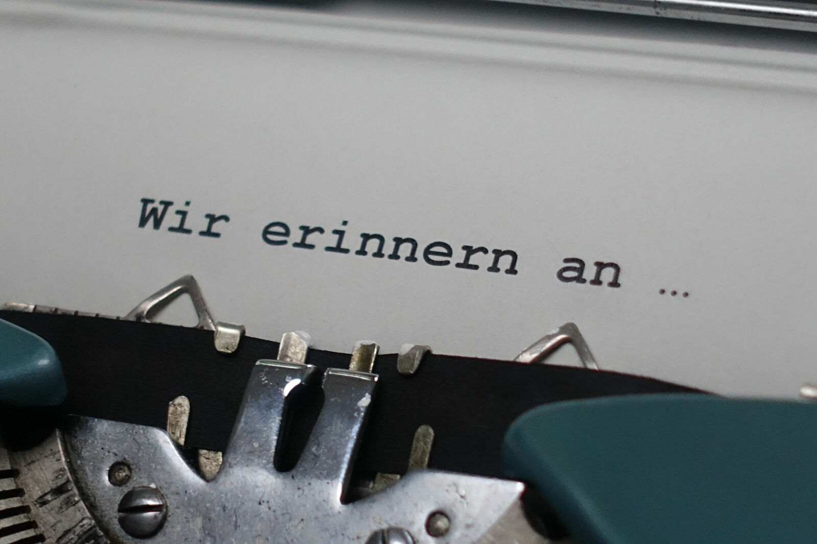 Nahaufnahme einer Schreibmaschine, auf deren Papier die Worte „Wir erinnern an …“ getippt sind.