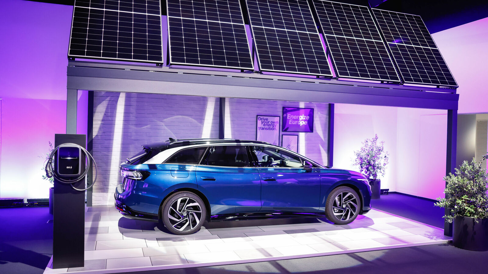 Volkswagen electric vehicle under a solar panel installation in a showroom. Symbolizing sustainable mobility and renewable energy.