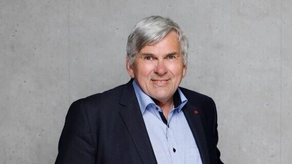 Jörg Hofmann in front of a grey wall.