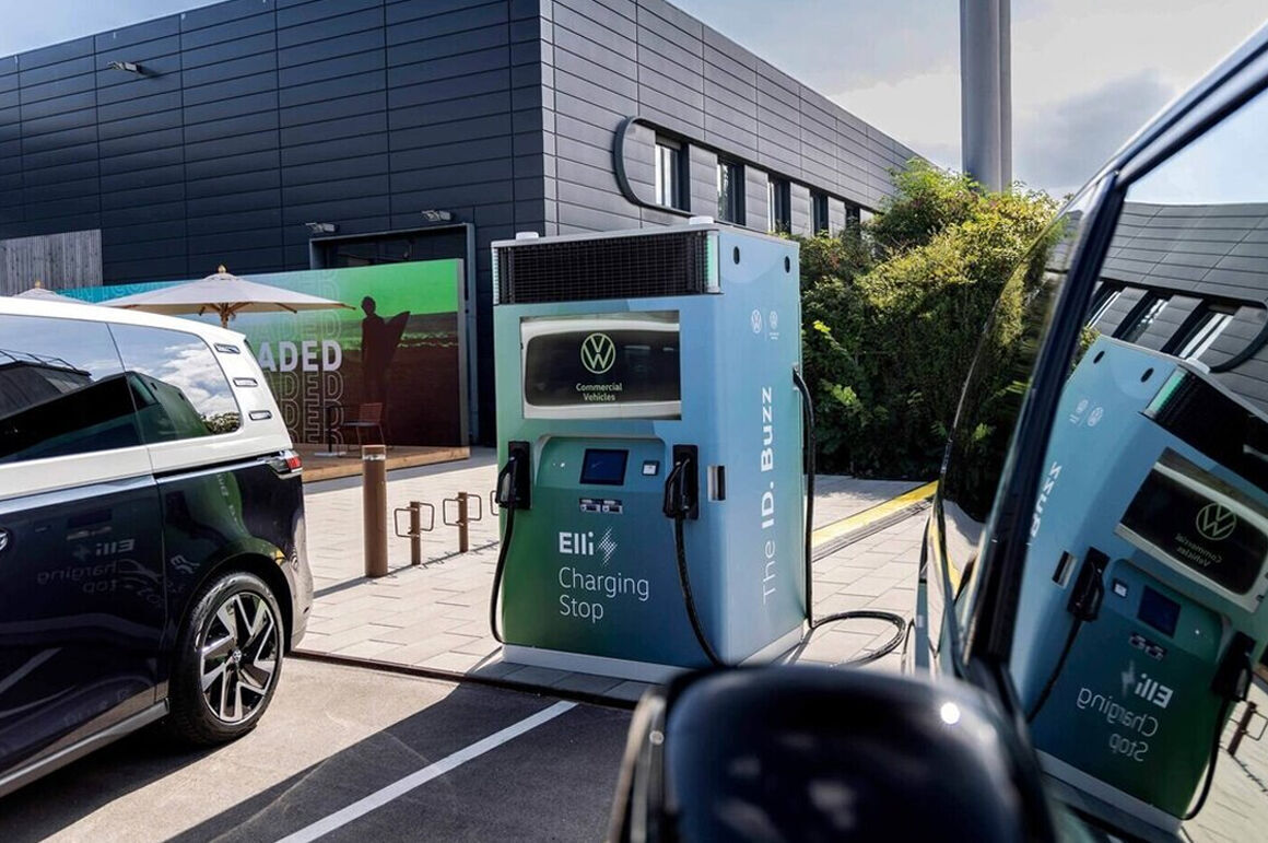 Electric car charging at a Volkswagen Elli charging station in front of a modern building.