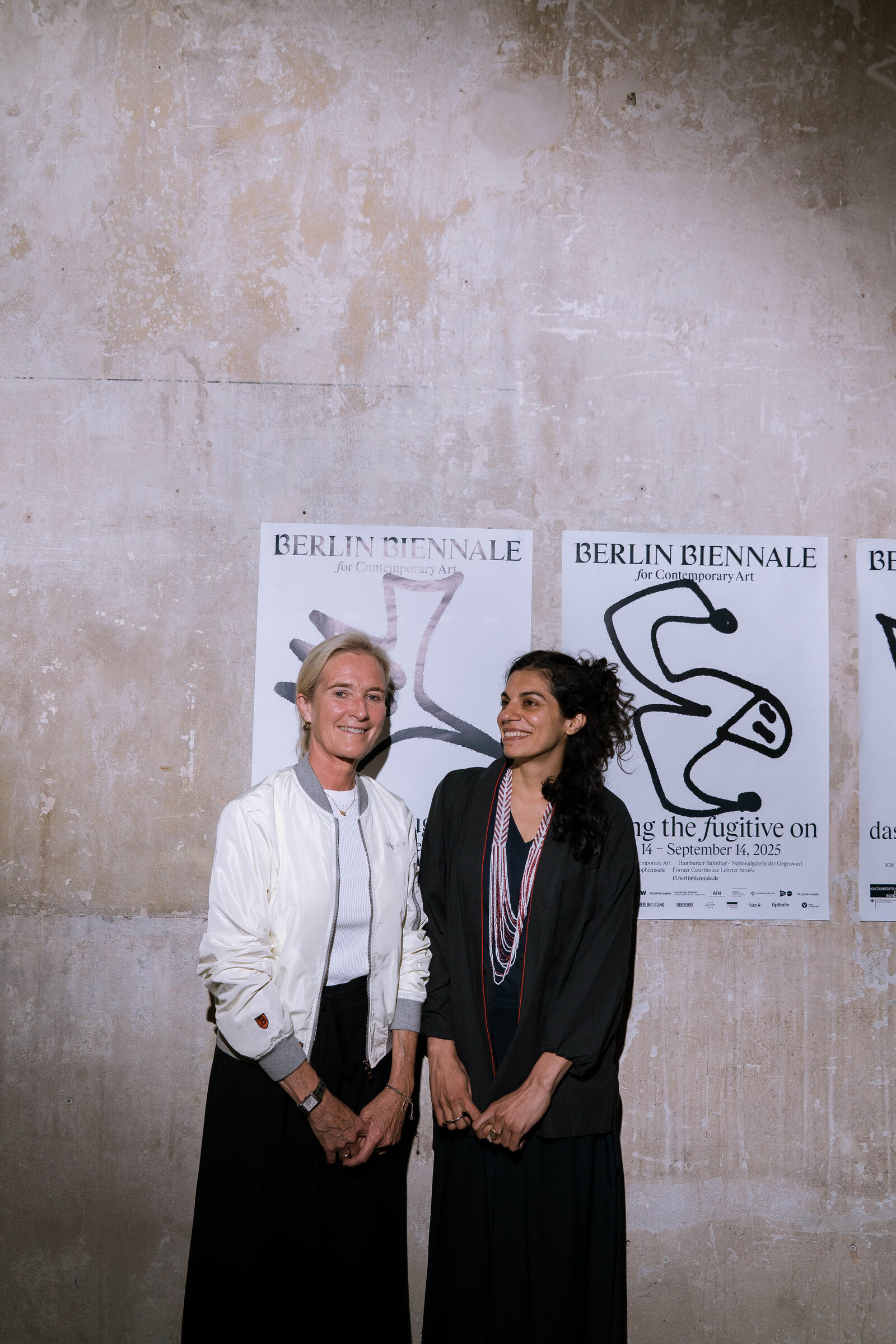 Zwei Frauen stehen vor einer Wand mit Plakaten