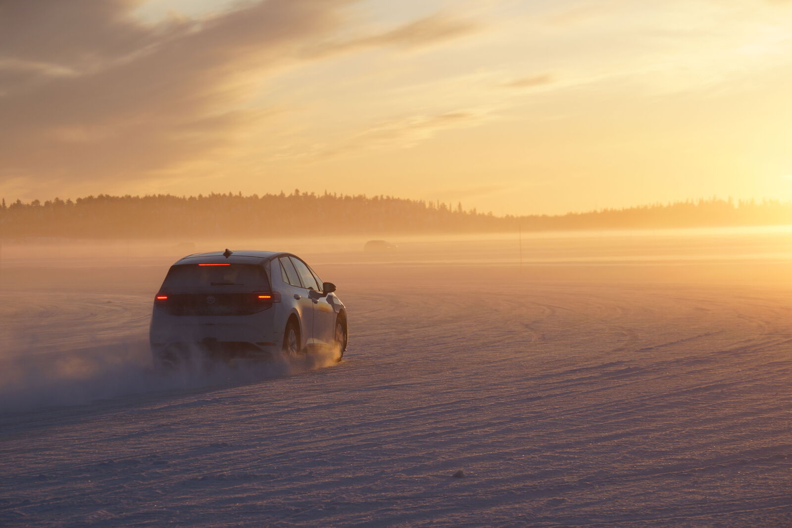 Auto fährt über eine verschneite Fläche im warmen Morgen-/Abendlicht, Nebel am Horizont.