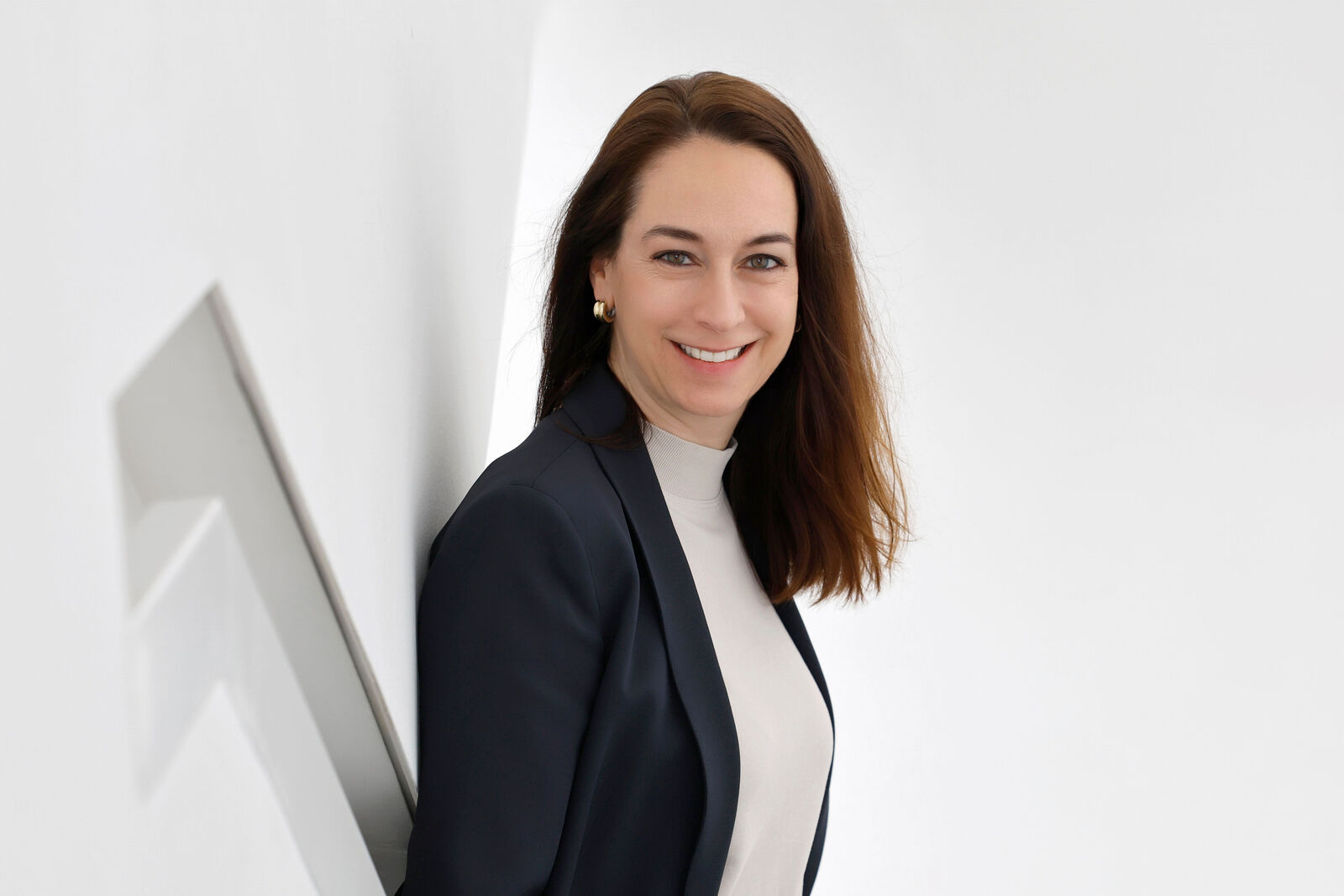 Corporate portrait of Christiane Zorn in a bright, modern interior. The portrait shows Christiane Zorn standing beside a wall and looking towards the camera.