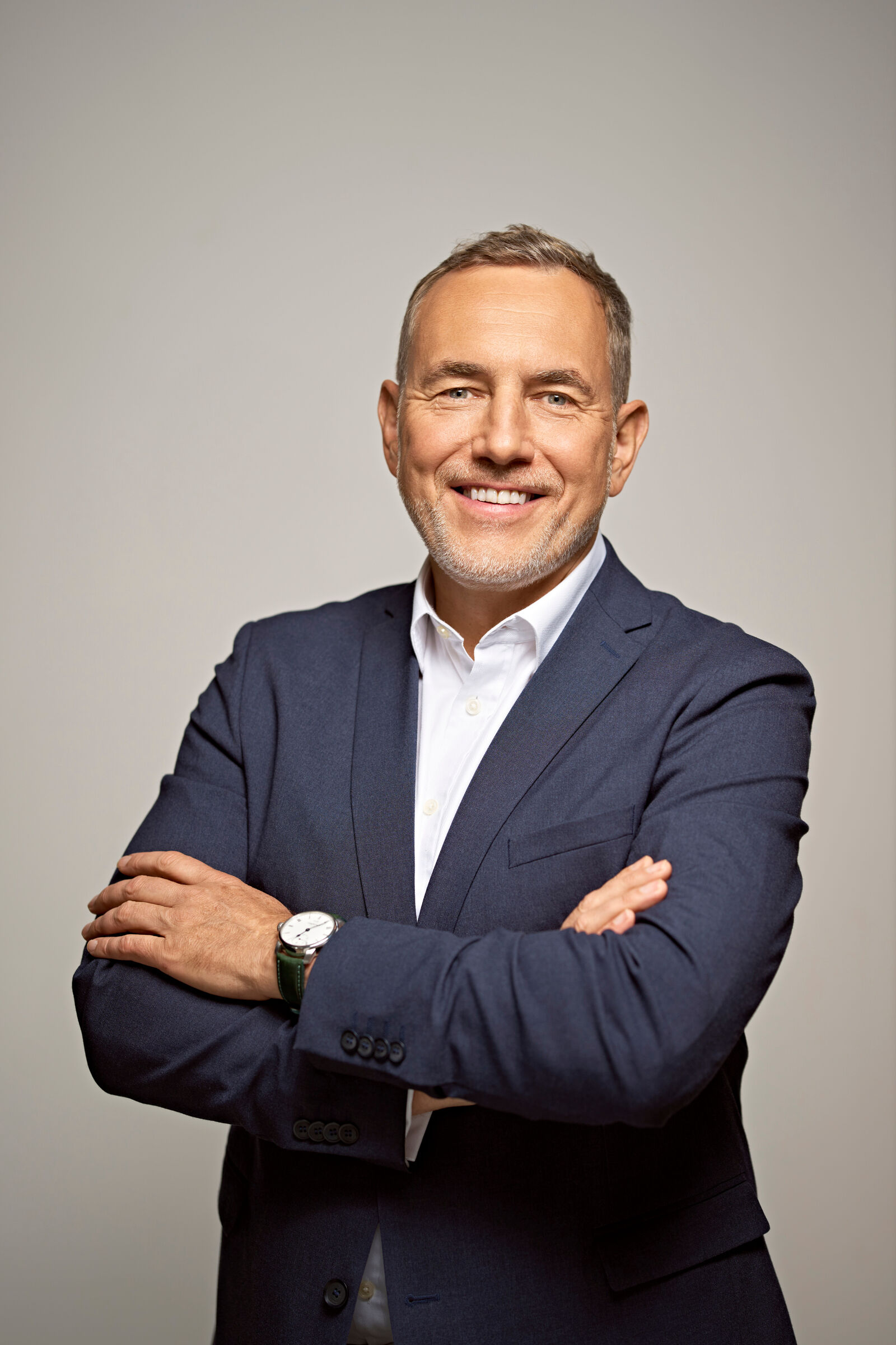Businessporträt von Martin Jahn in dunklem Anzug und weißem Hemd vor neutralem Hintergrund. Die Person steht mit verschränkten Armen vor der Kamera.